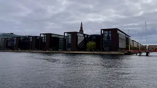 Modern waterfront office buildings stand beside the harbor beneath the spire of the Church of Our Saviour.