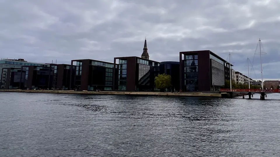 Modern waterfront office buildings stand beside the harbor beneath the spire of the Church of Our Saviour.