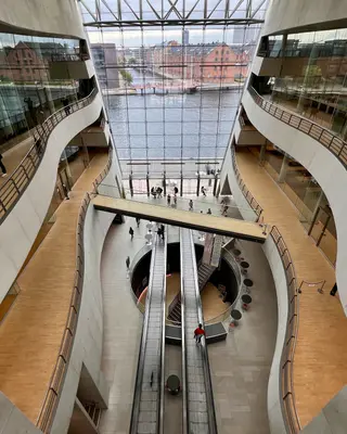 The Black Diamond’s soaring atrium has curved white balconies and escalators facing a glass wall overlooking the waterfront.