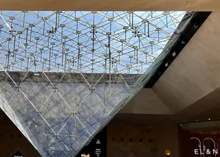 The Inverted Pyramid of the Louvre rises beneath a geometric glass ceiling inside the Carrousel du Louvre.