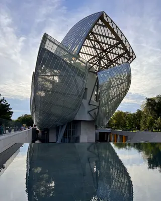 The Fondation Louis Vuitton's sweeping glass-and-steel sails rise above a reflecting pool and surrounding trees.
