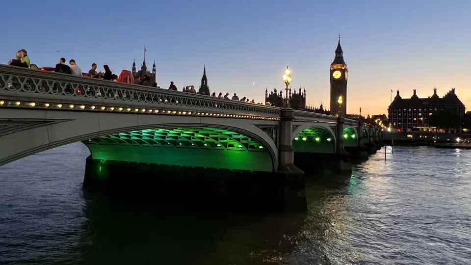 Westminster Bridge spans the River Thames at dusk, with the illuminated Big Ben and the Palace of Westminster rising behind it.