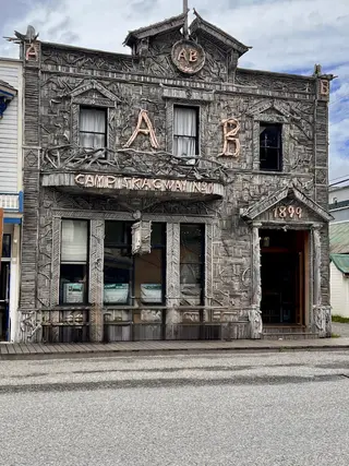 The Arctic Brotherhood Hall features a weathered driftwood-covered facade with an "A B" emblem and a "Camp Skagway No. 1" sign.