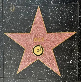 A red terrazzo star marked "WAR" and a record emblem is set into the Hollywood Walk of Fame sidewalk.