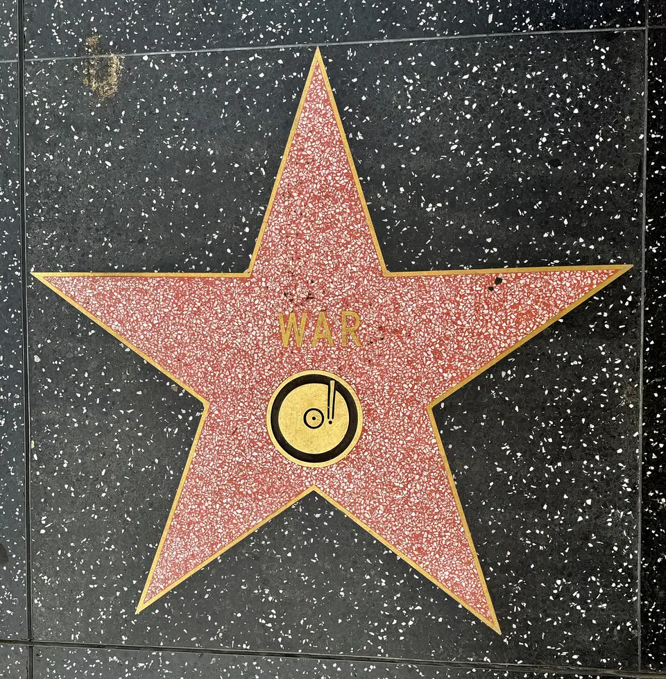 A red terrazzo star marked "WAR" and a record emblem is set into the Hollywood Walk of Fame sidewalk.